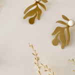 Gold and silver earrings on a light background with dried plants.