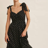 Woman wearing a black dress with bow straps on a beige background