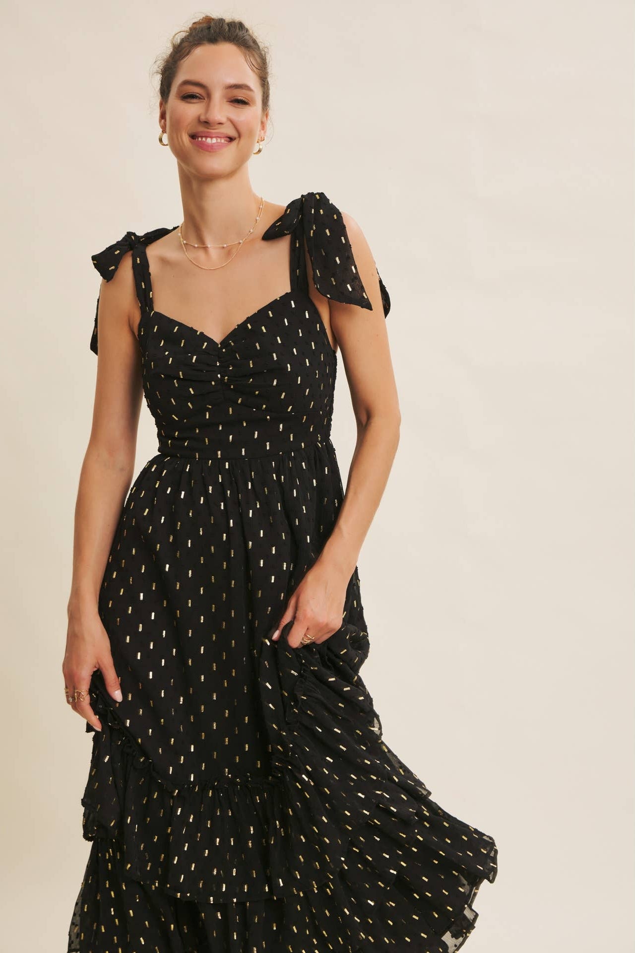 Woman wearing a black dress with bow straps on a beige background