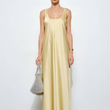 Woman wearing a light yellow dress holding a gray bag on a white background