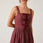 Woman wearing a red plaid dress against a plain background