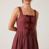 Woman wearing a red plaid dress against a plain background