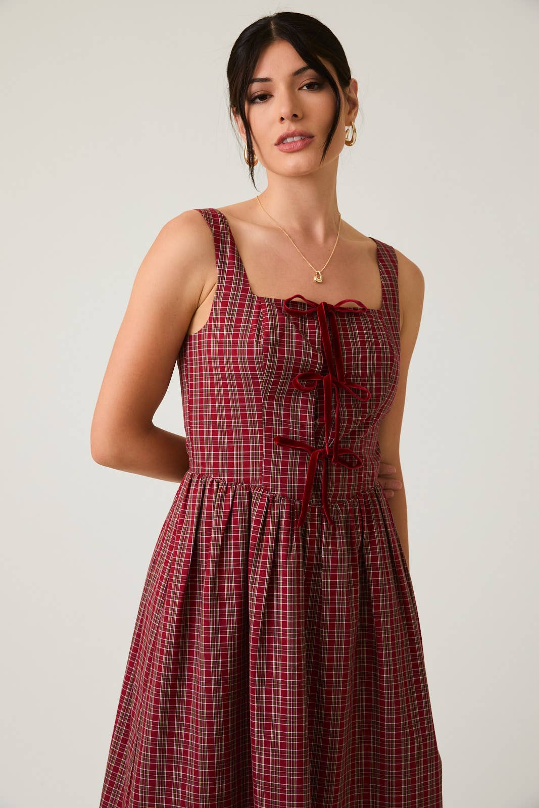 Woman wearing a red plaid dress against a plain background
