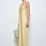 Woman wearing a long yellow dress holding a gray bag against a white background